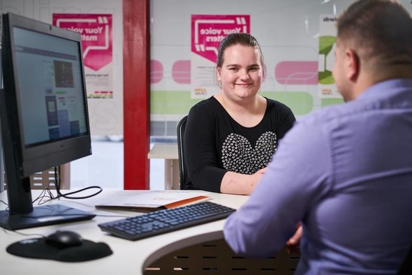 Female DES participant talking to APM consultant at desk