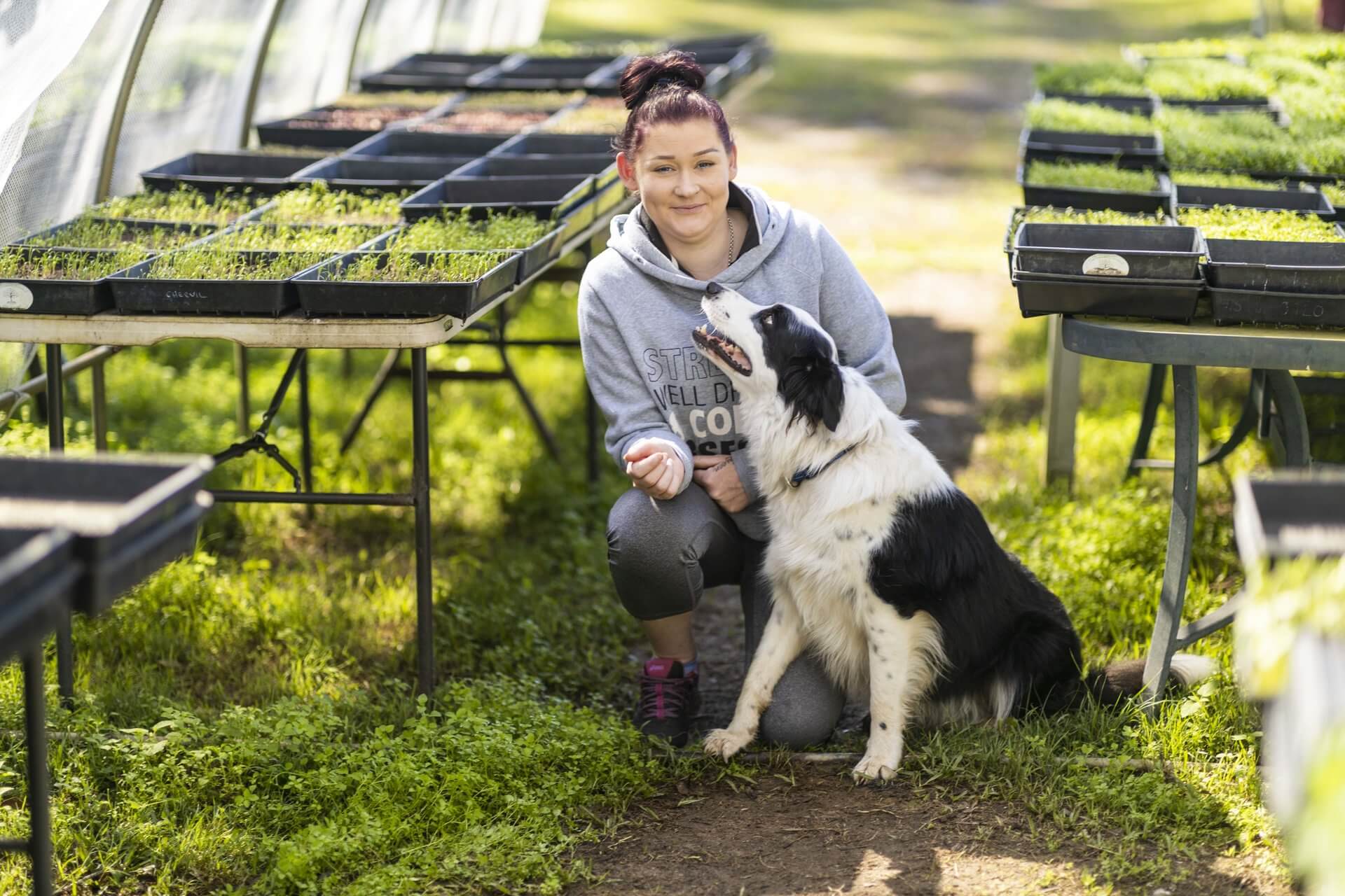 DES participant Emma smiles between rows of plants in a nursery