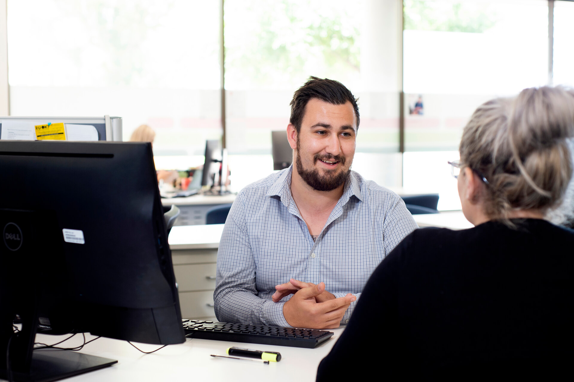 employee talking with a woman at a desk