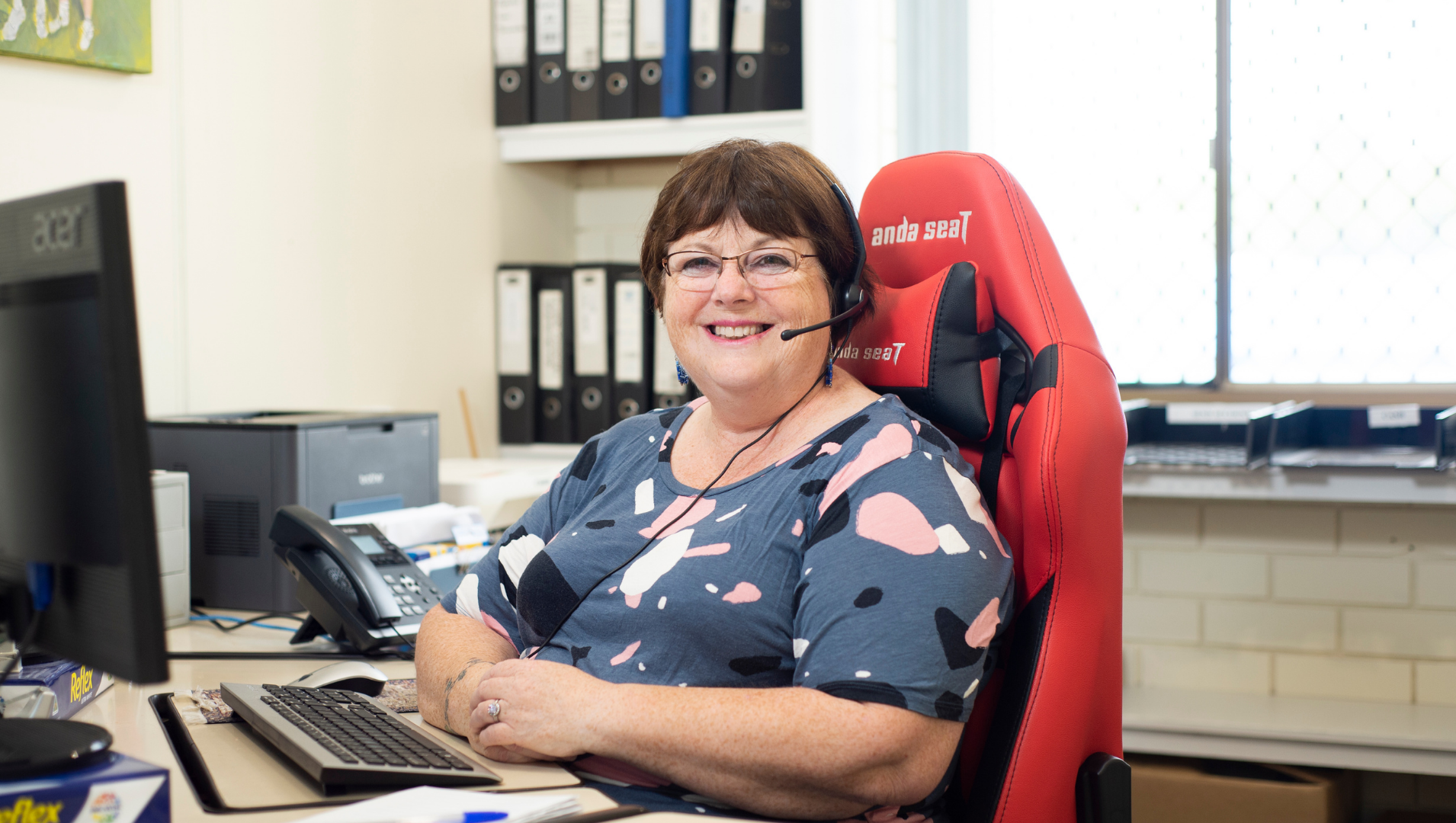 woman with a headset in front of a computer smiling