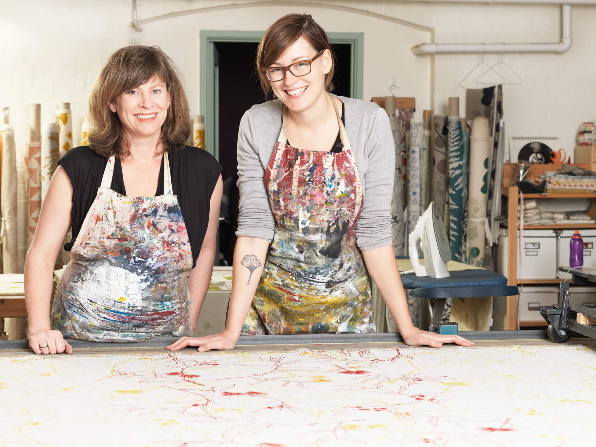 two woman wearing aprons smiling