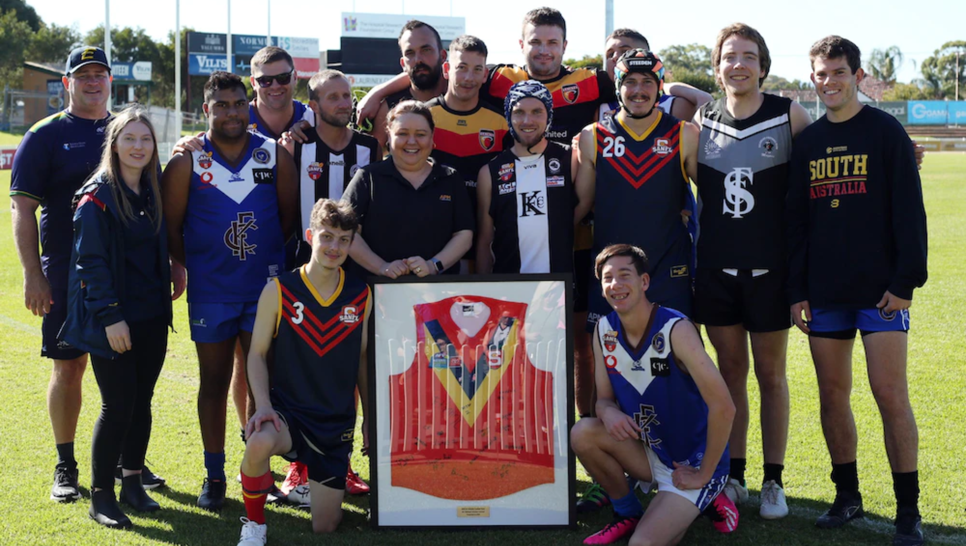 State Inclusive team posing around a framed jumper