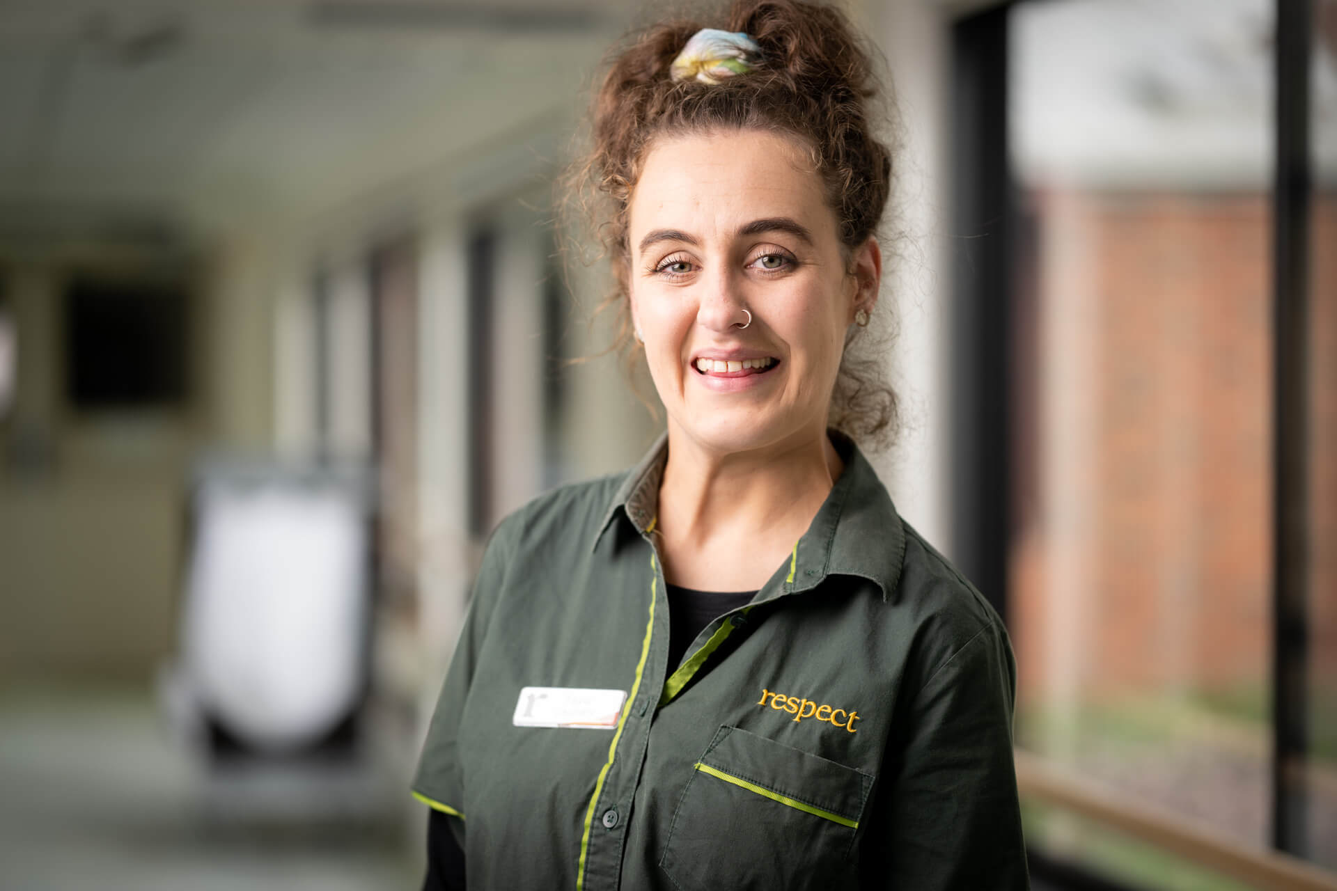 Tayla smiles in her olive green staff uniform