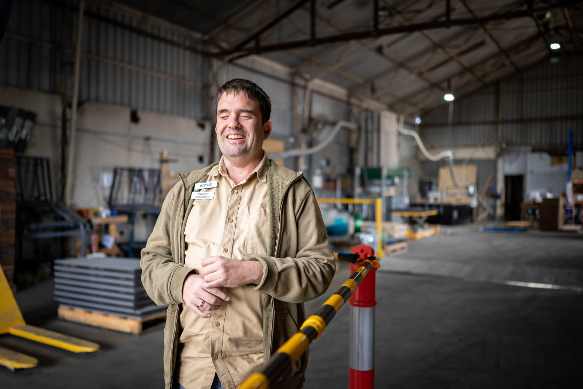 Kyle smiles next to the safety barrier with a warehouse behind him