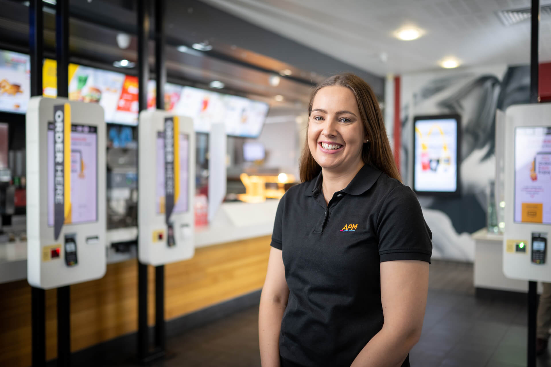 Samantha a young APM employee smiles in a black polo top