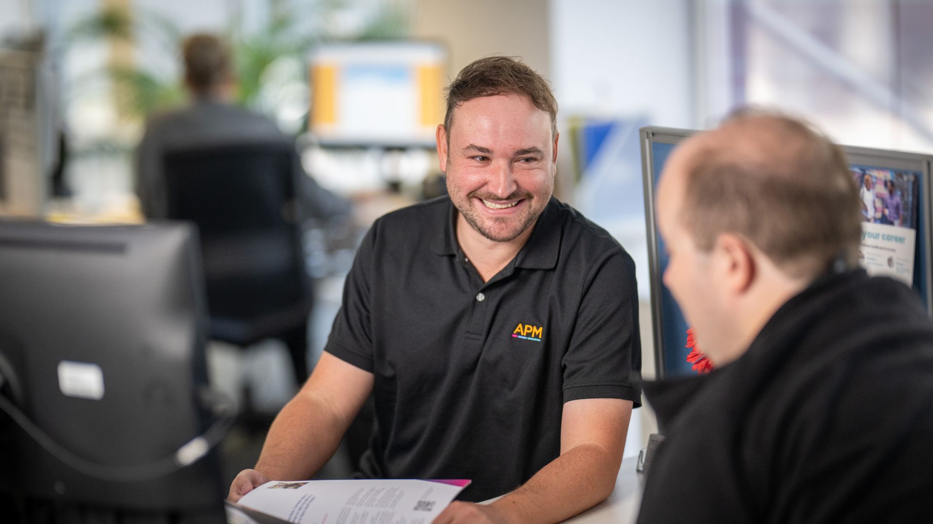 APM EC Adam listens to a DES participant inside an APM office