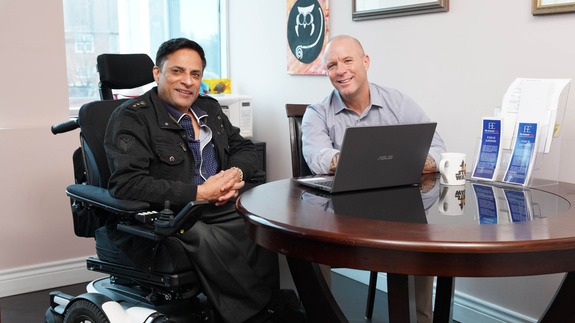 a man in a wheelchair speaks to a worker at a desk