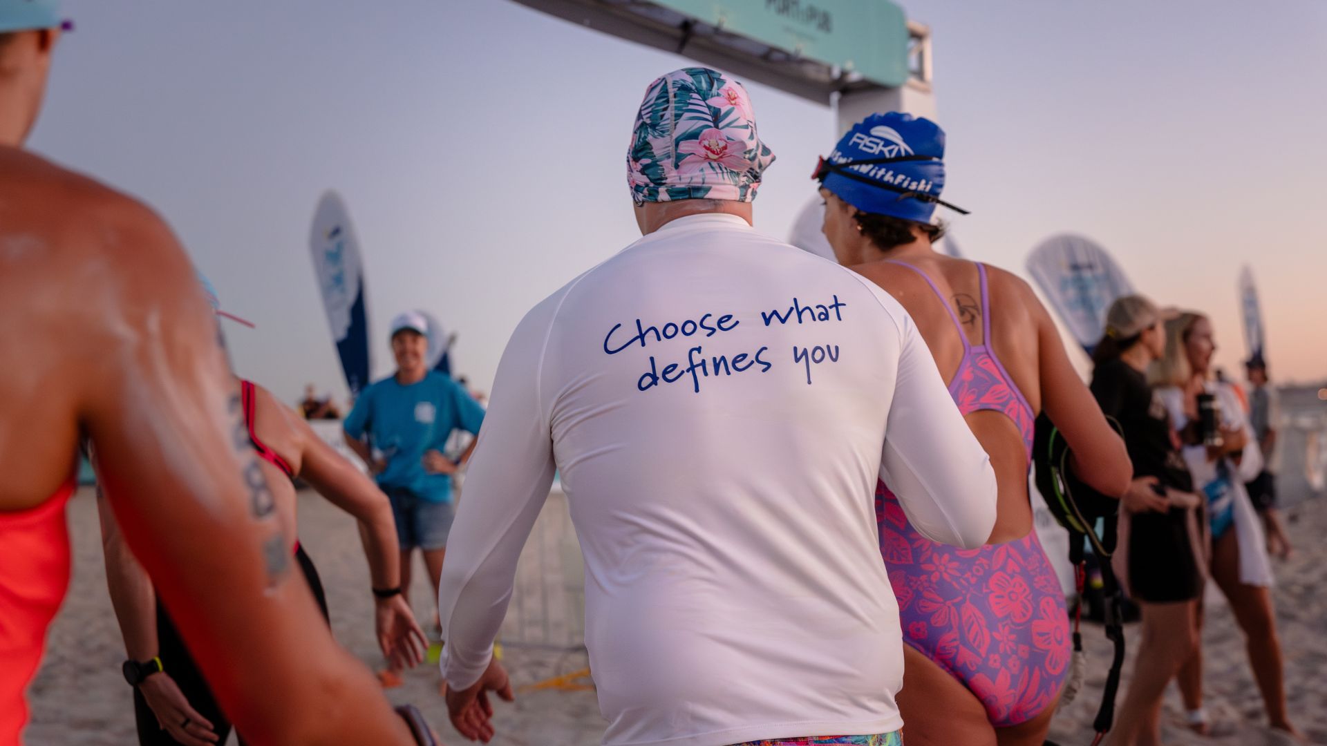 Open water swimmers gather on the beach before a race, capturing the start of a marathon swimming event and the team environment behind long-distance challenges.