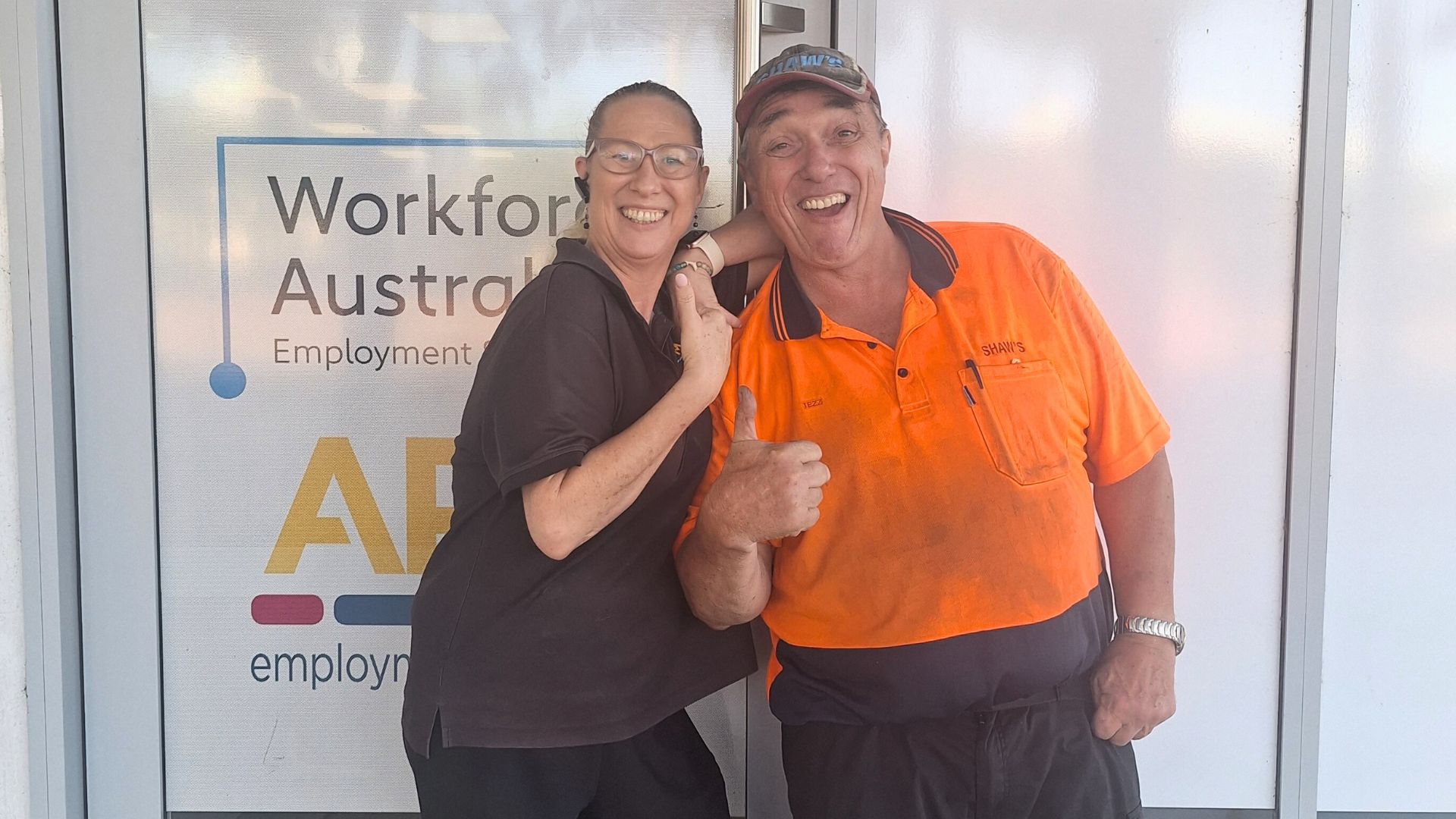 A man smiles and gives a thumbs up with a woman outside APM