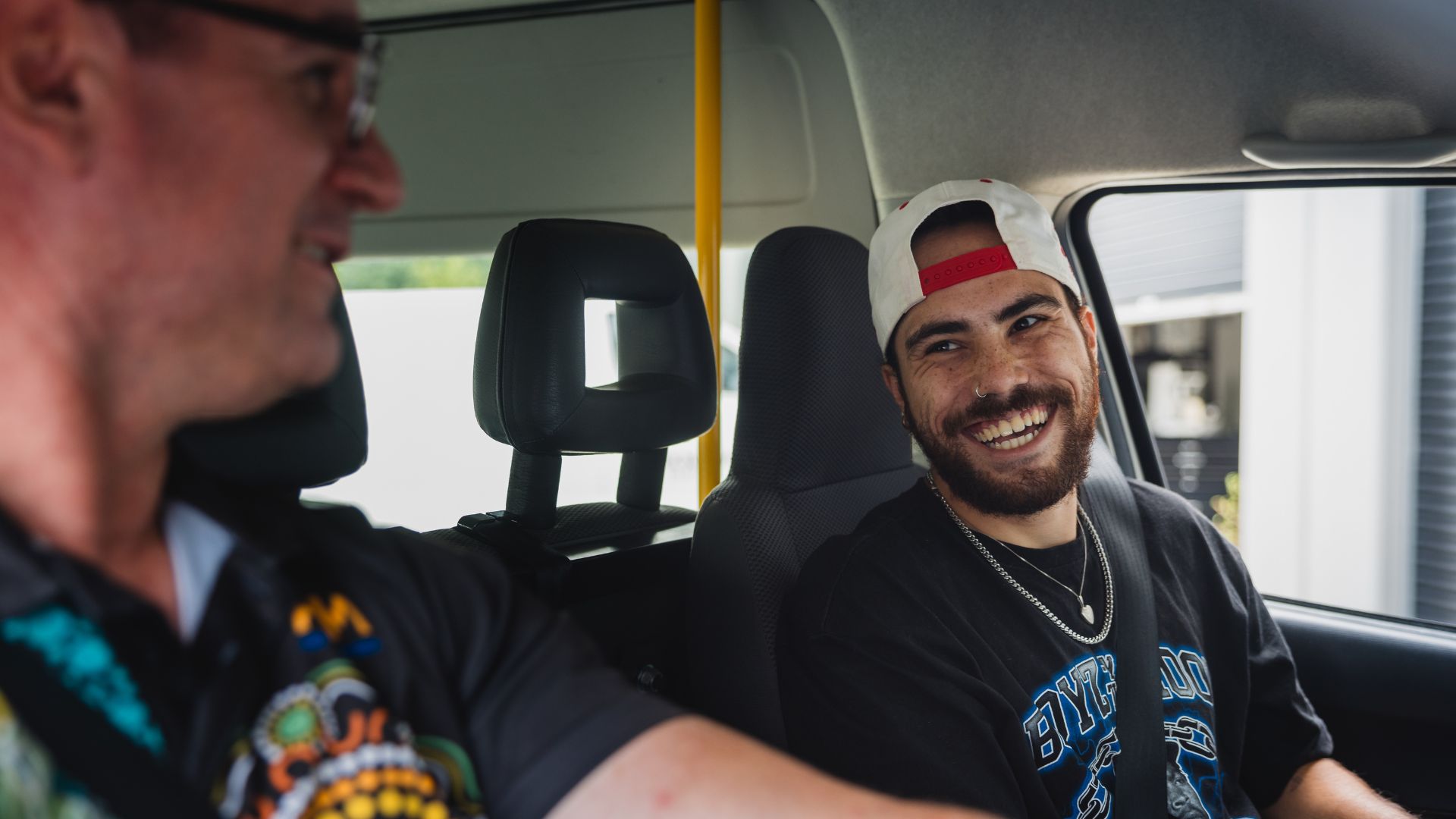 Martin and Balan sitting in a car smiling at each other