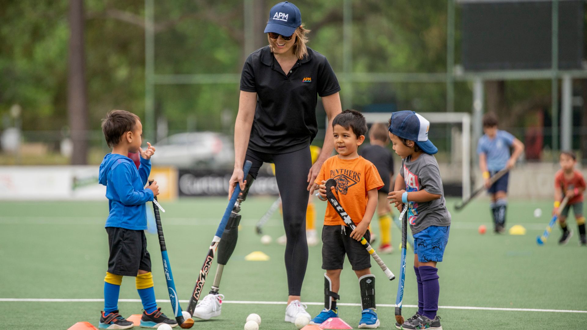 Ellie Cole showing young children how to play hockey