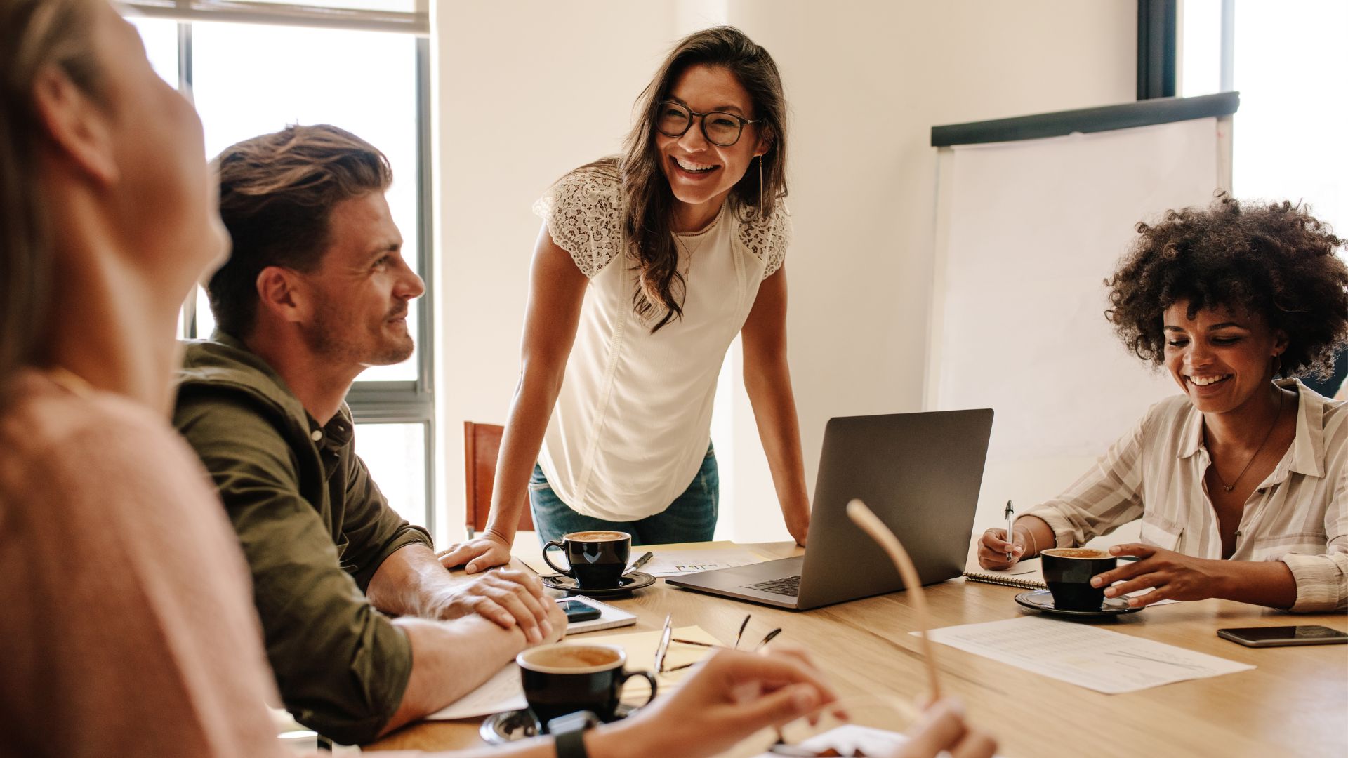 Woman speaks to a group for training while writing on clear board