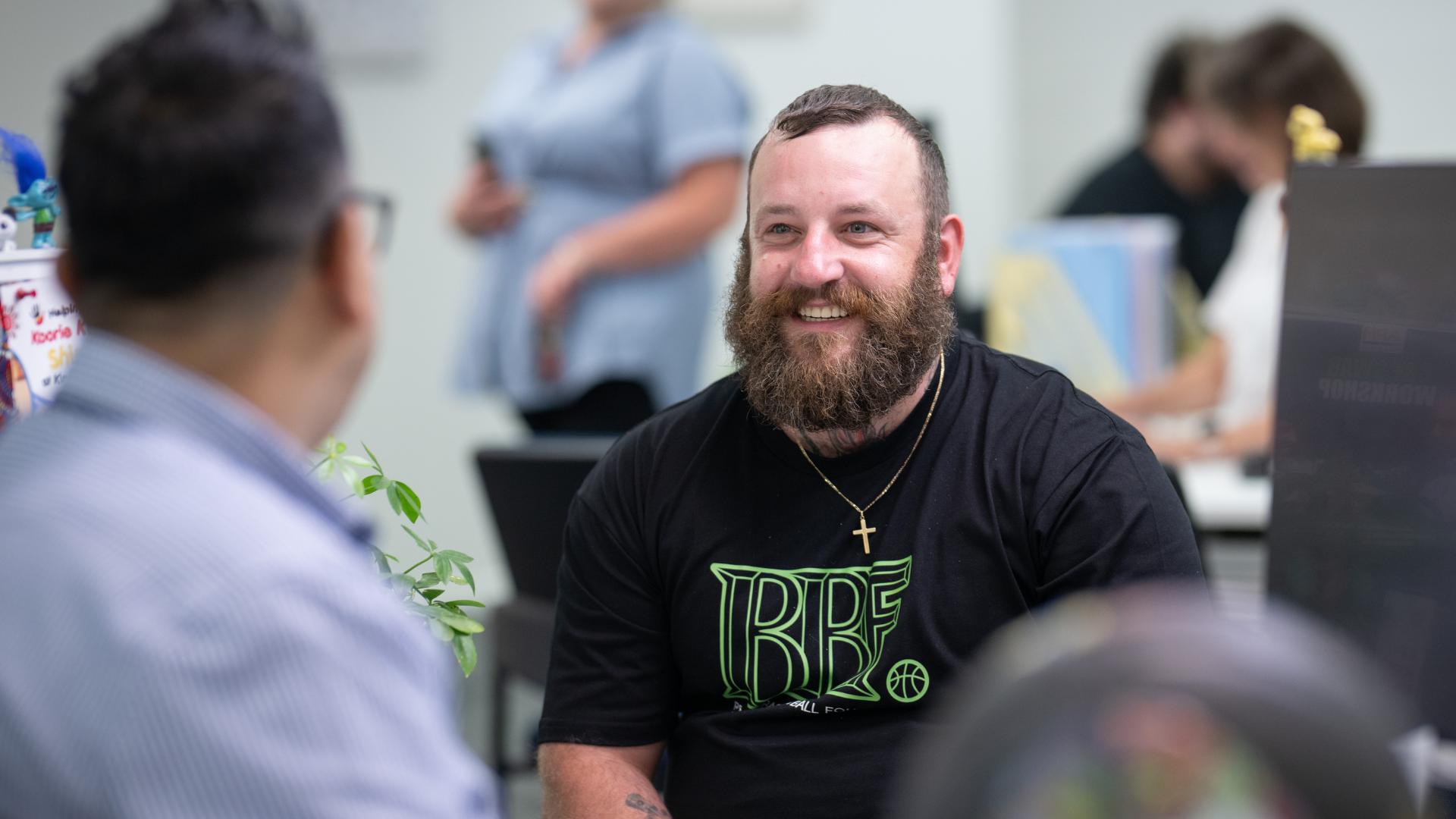 A man smiles at a desk with an APM consultant