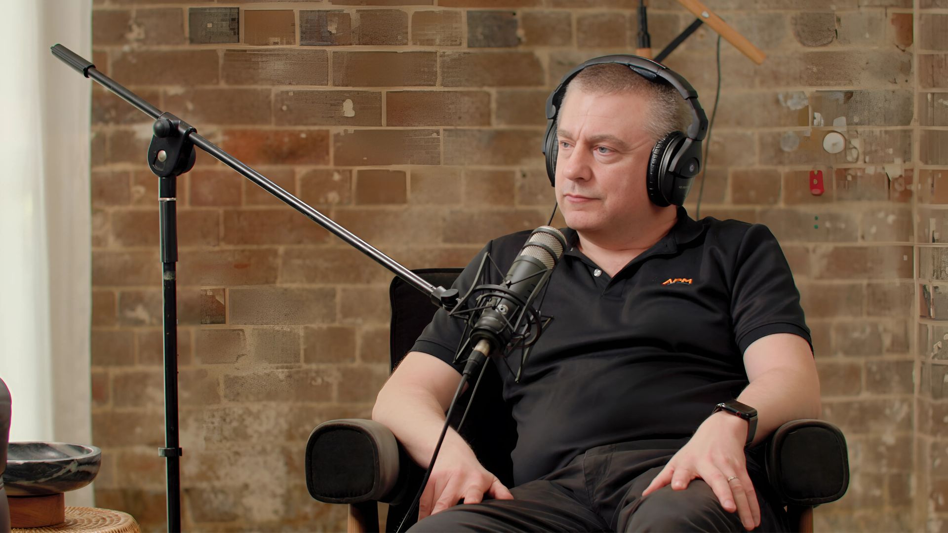 Graham in a black APM top sitting in front of a microphone