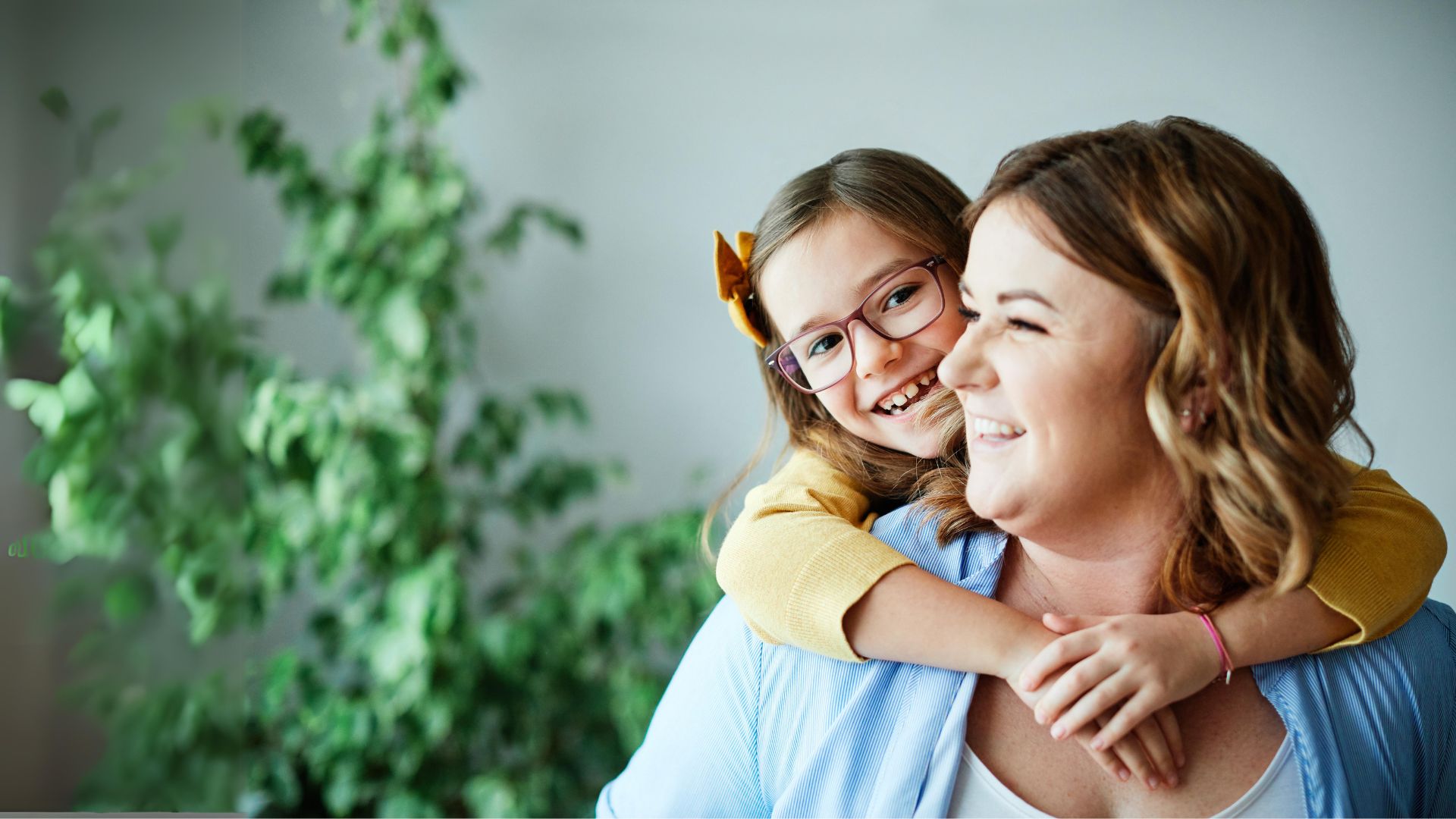 A young girl in glasses hugs her mum