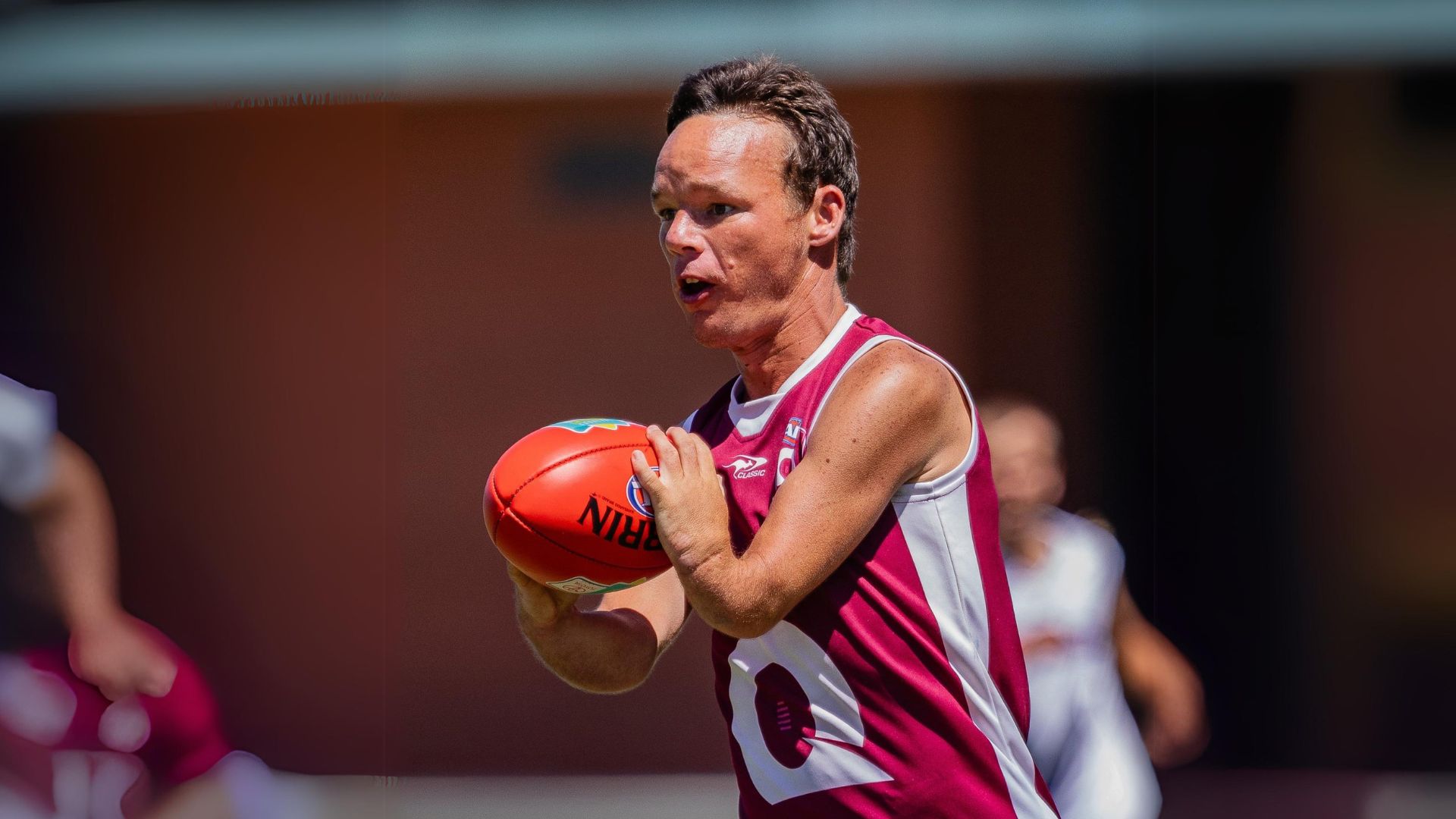 An inclusive AFL player with the ball