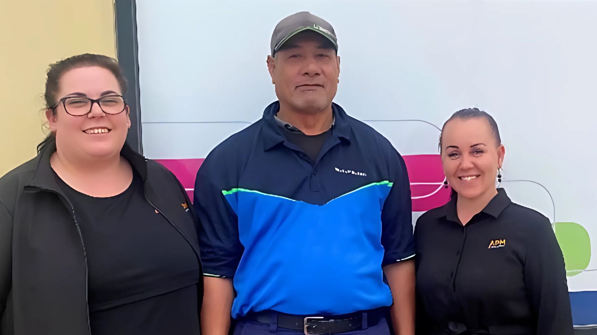 Iefata stands between two women in black APM polos smiling