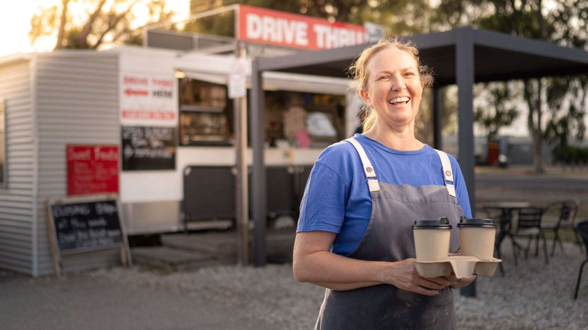 A woman holds coffees outside a cafe
