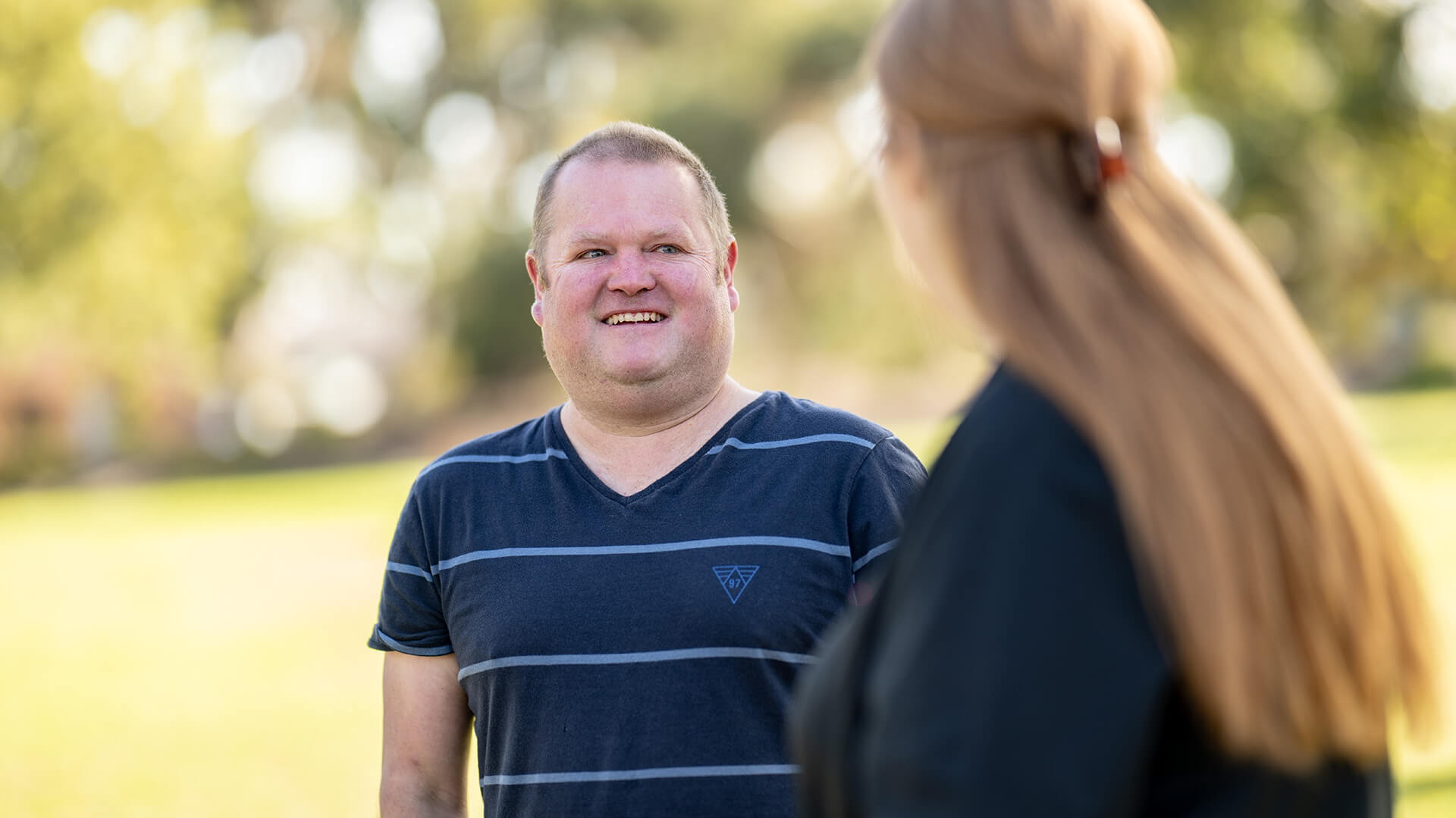 Man in blue tshirt smiles at an APM team member