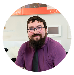 Bearded man with glasses wearing a formal shirt and tie smiles