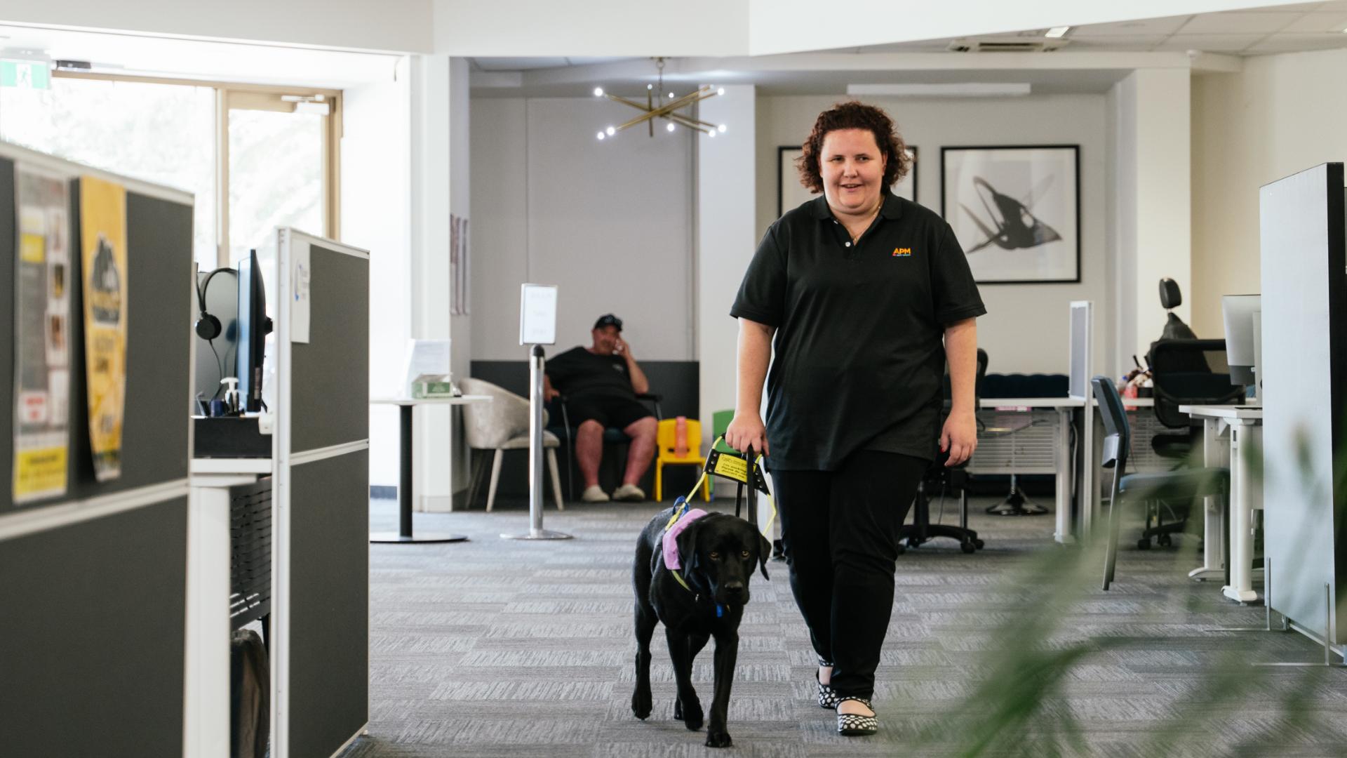 APM team member with a guide dog walking through an office